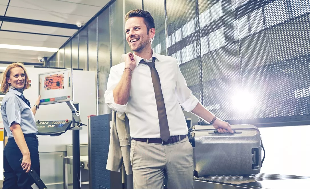 FastTrack Vienna Airport A man reaches for his suitcase after security control at the airport / Copyright: VIE
